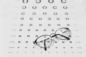5 Medicare Basics You Should Know Pair of eyeglasses sitting on top of black and white eye exam.