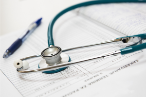 Green stethoscope and pen on top of medical bill. 