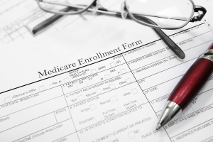 Medicare enrollment form with a red pen and glasses on top of it, ready to go for the Medicare Special Enrollment Period.