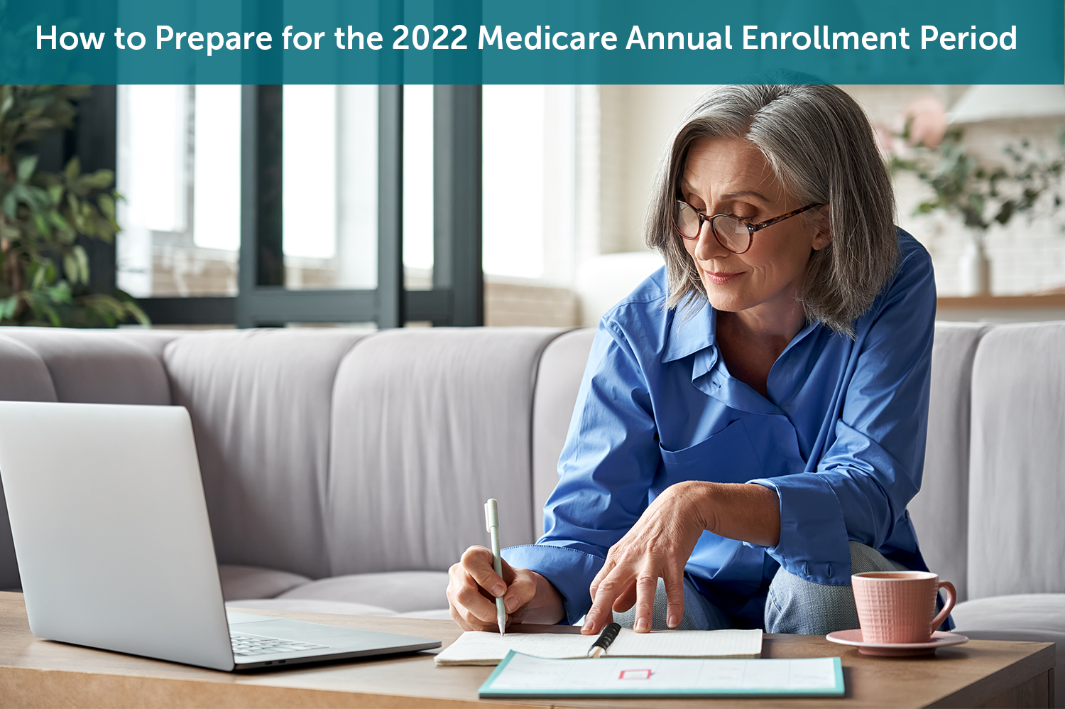 A white senior woman sitting on a grey couch in front of her laptop preparing for the Medicare Annual Enrollment Period