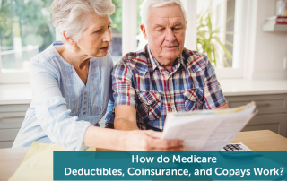 A senior man and senior woman looking over their bills for their Medicare deductibles and copays on a gray couch.